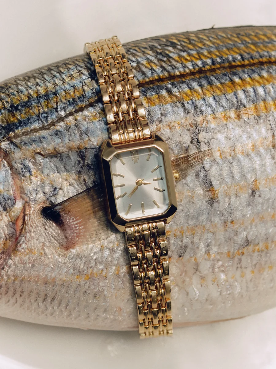 Goldene Armbanduhr auf einem Fisch